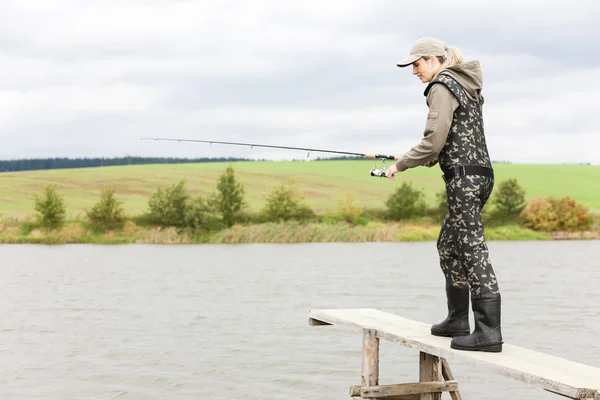 Mujer pescando en muelle en estanque —  Fotos de Stock