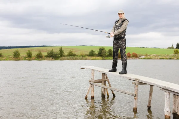 Mulher pesca no cais na lagoa — Fotografia de Stock