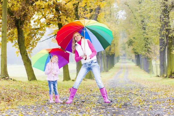 Mor och hennes dotter med paraplyer i höstlig gränd — Stockfoto