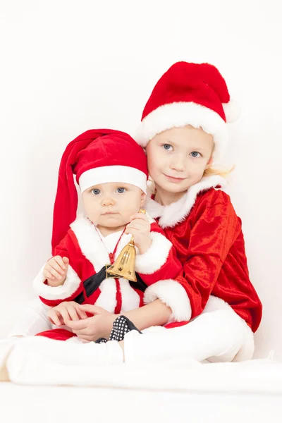 Duas meninas como Papai Noel com um sino — Fotografia de Stock