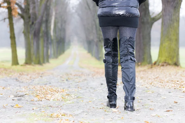 Détail de la femme portant des vêtements noirs et des bottes dans l'allée automnale — Photo