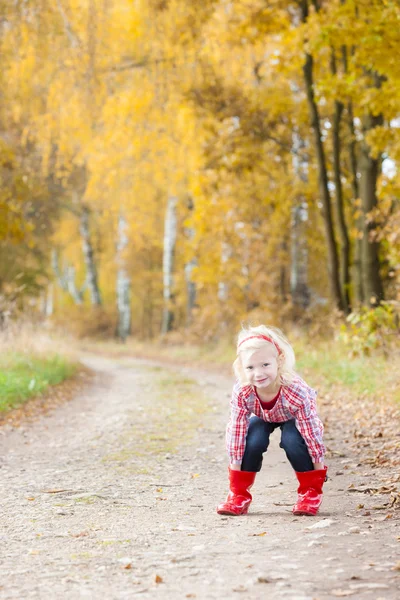 Liten flicka klädd i gummi stövlar i höstlig gränd — Stockfoto