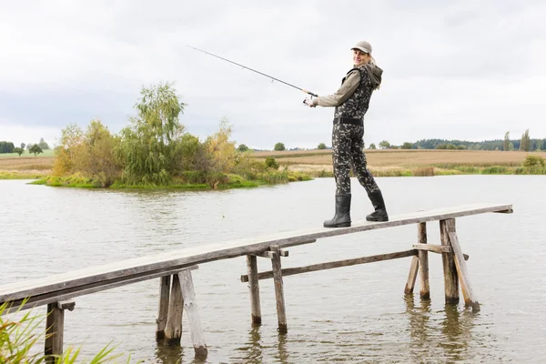 Kvinna fiske på piren vid dammen — Stockfoto