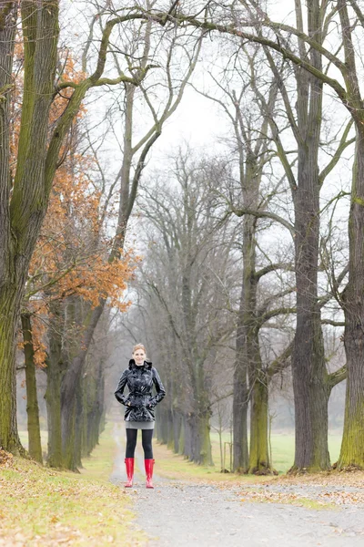 Woman wearing rubber boots in autumnal alley — Stock Photo, Image