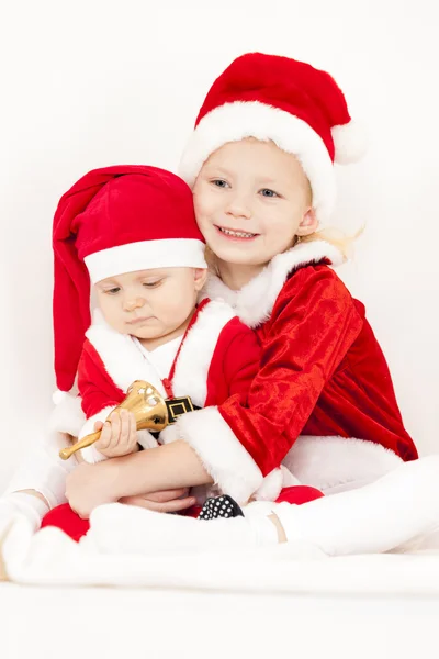 Two little girls as Santa Clauses with a bell — Stock Photo, Image