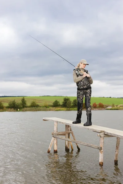 Mujer pescando en muelle en estanque — Foto de Stock