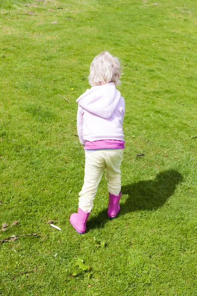 Little girl wearing rubber boots on lawn Stock Image