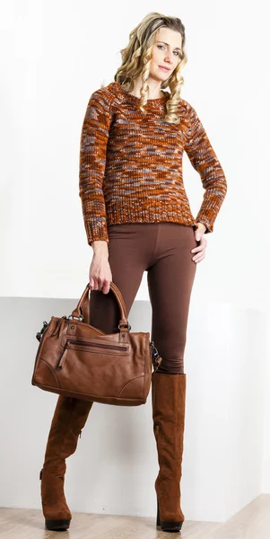 Stehende Frau in brauner Kleidung und Stiefeln mit Handtasche — Stockfoto