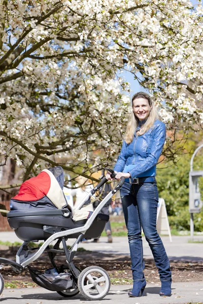 Mulher com um carrinho de bebê no passeio de primavera — Fotografia de Stock