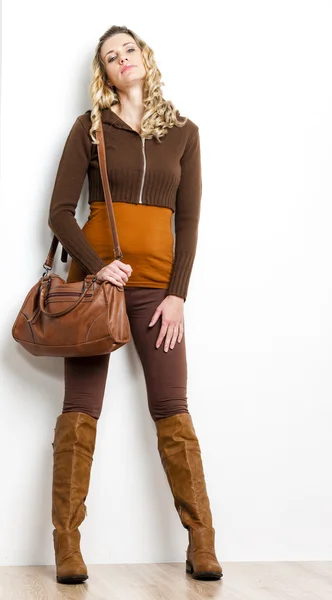 Standing woman wearing brown clothes and boots with a handbag — Stock Photo, Image