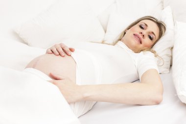 Hamile kadın yatakta dinleniyor.