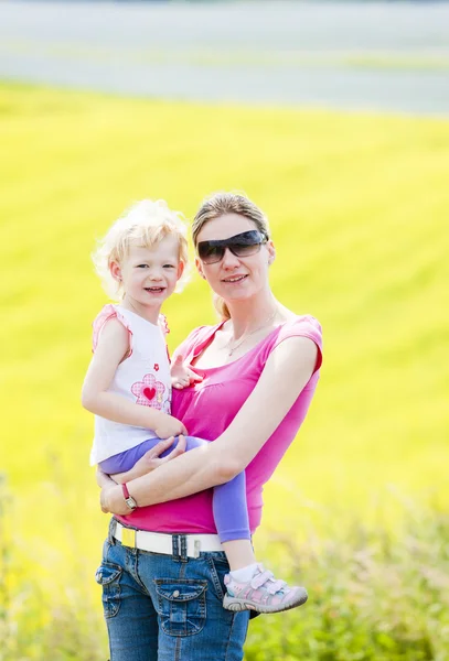Mother with her daughter at rape field — Stock Photo, Image