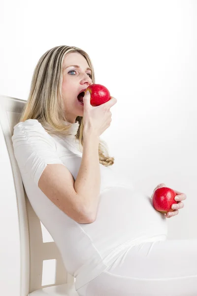 Mujer embarazada comiendo manzana roja — Foto de Stock