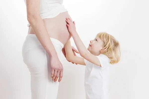 Meisje met haar zwangere moeder — Stockfoto