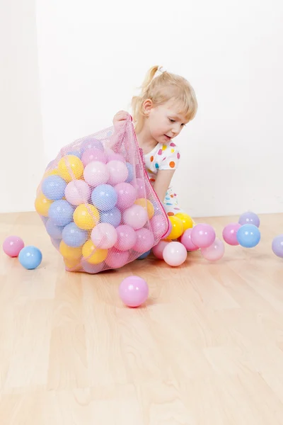 Kleines Mädchen spielt mit Bällen — Stockfoto