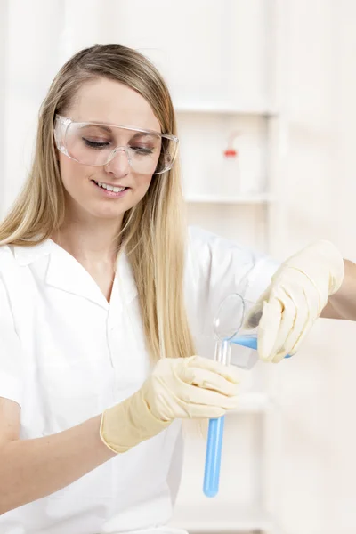 Mujer joven haciendo experimento en laboratorio —  Fotos de Stock