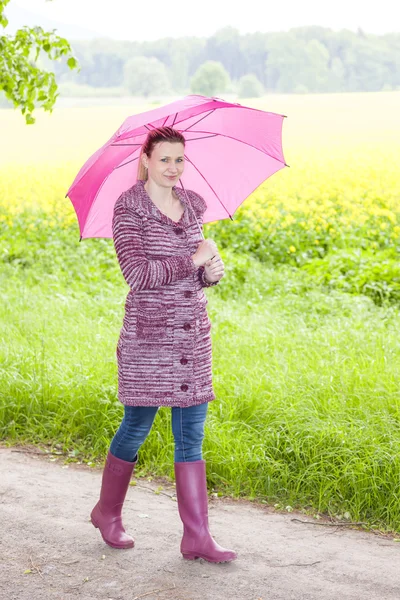 Frau trägt Gummistiefel mit Regenschirm — Stockfoto
