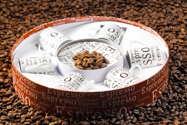 Kaffeetassen in einer Schachtel auf Kaffeebohnen gelagert — Stockfoto