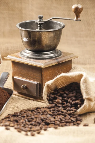 Naturaleza muerta de los granos de café en la bolsa de yute con molinillo de café —  Fotos de Stock