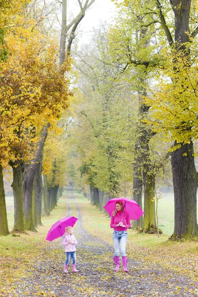 Mãe e sua filha com guarda-chuvas em beco outonal — Fotografia de Stock