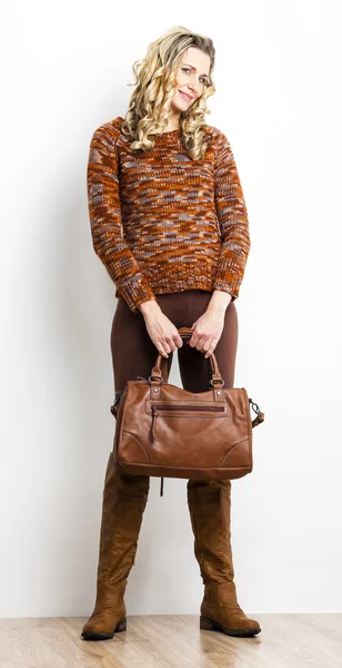 Kahverengi elbiseler ve bir çanta ile bot giyen duran kadın — Stok fotoğraf
