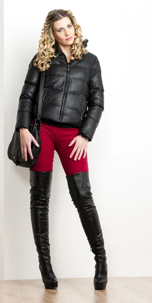 Mulher de pé vestindo roupas da moda e botas com uma mão — Fotografia de Stock