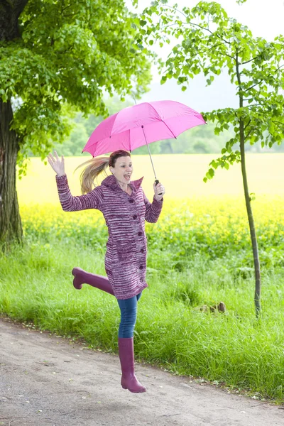 Žena nosí gumové boty s deštníkem v jarní přírodě — Stock fotografie