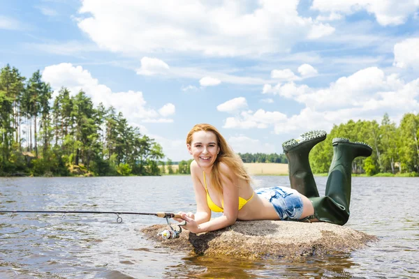 Mujer joven pescando en el estanque durante el verano — Foto de Stock