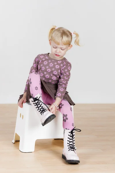 Little girl putting on boots — Stock Photo, Image