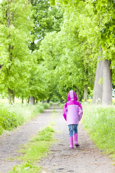 Petite fille portant des bottes en caoutchouc dans l'allée du printemps — Photo