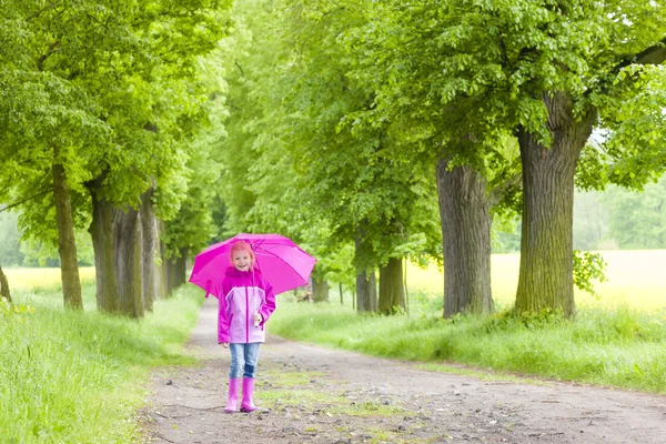 Kleines Mädchen in Gummistiefeln mit Regenschirm in der Frühlingsgasse — Stockfoto