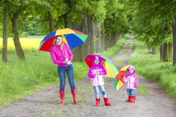 Matka i jej córki z parasolami w wiosna zaułek — Zdjęcie stockowe