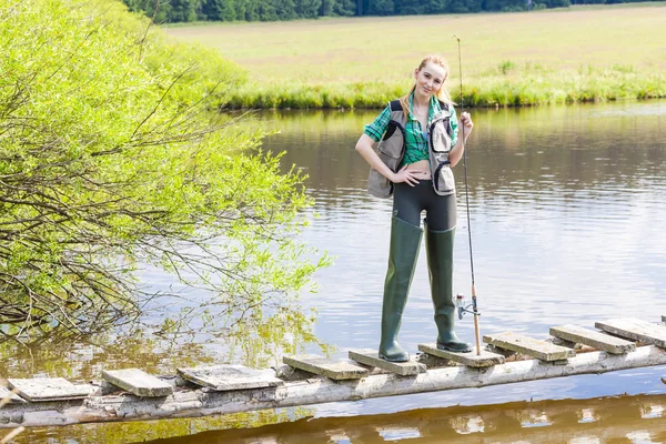 Young woman fishing on pier at pond — Stock Photo, Image