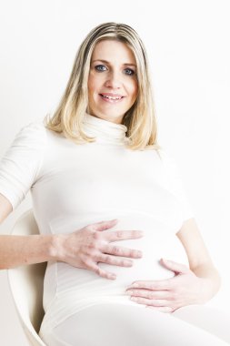 Beyaz elbise giyen hamile kadın oturuyor