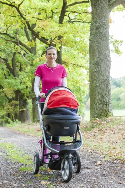 Woman with a pram on walk — Stock Photo, Image