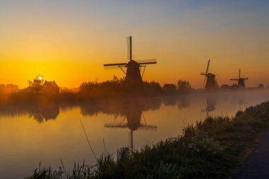 Hollanda 'nın Kinderdijk şehrinde güneş doğmadan hemen önce renkli gökyüzü olan geleneksel Hollanda yel değirmenleri