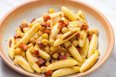 Domuz pastırmalı, soğanlı ve bezelyeli schupfnudel.