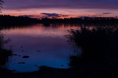 Güney Bohemya, Çek Cumhuriyeti 'nin Pisek kasabası yakınlarındaki Rezabinec gölünün üzerinde gün batımı