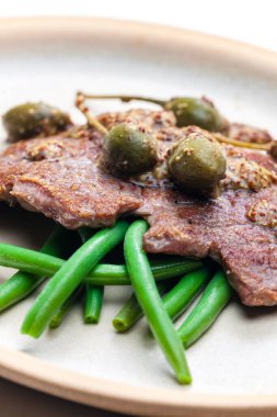 Kapari ve yeşil fasulyeli hardal soslu domuz bifteği.
