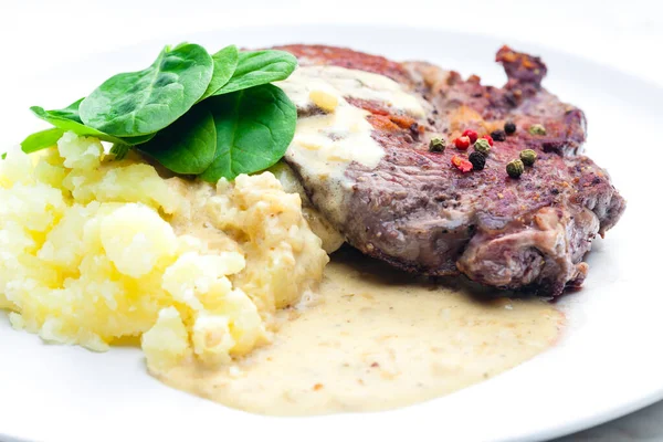 beef steak with sauce, mashed potatoes and spinach leaves