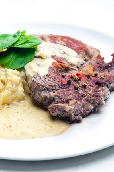 beef steak with sauce, mashed potatoes and spinach leaves