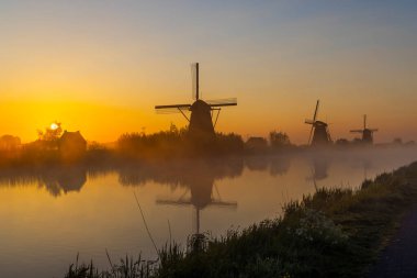 Hollanda 'nın Kinderdijk şehrinde güneş doğmadan hemen önce renkli gökyüzü olan geleneksel Hollanda yel değirmenleri