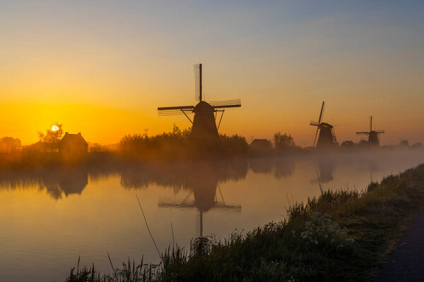 Traditional Dutch windmills with a colourful sky just before sunrise in Kinderdijk, The Netherlands