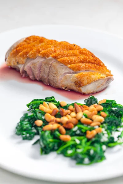 roasted duck breast served with salad of spinach leaves and pine nuts