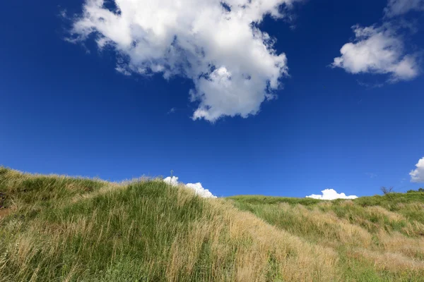 Colina sob céu azul com nuvens — Fotografia de Stock