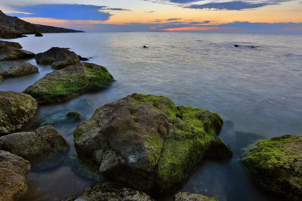 Pedras verdes no fundo por do sol mar — Fotografia de Stock