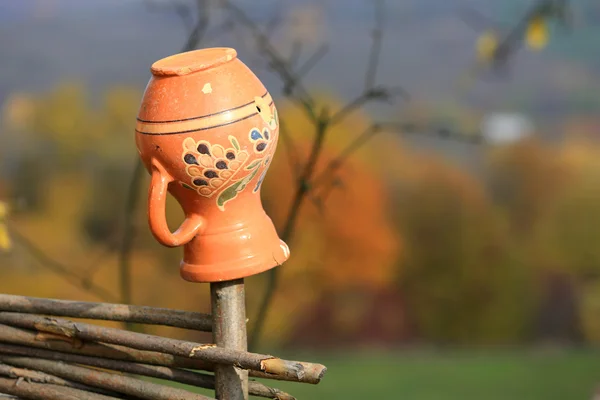 Clay jug on wooden fence — Stock Photo, Image