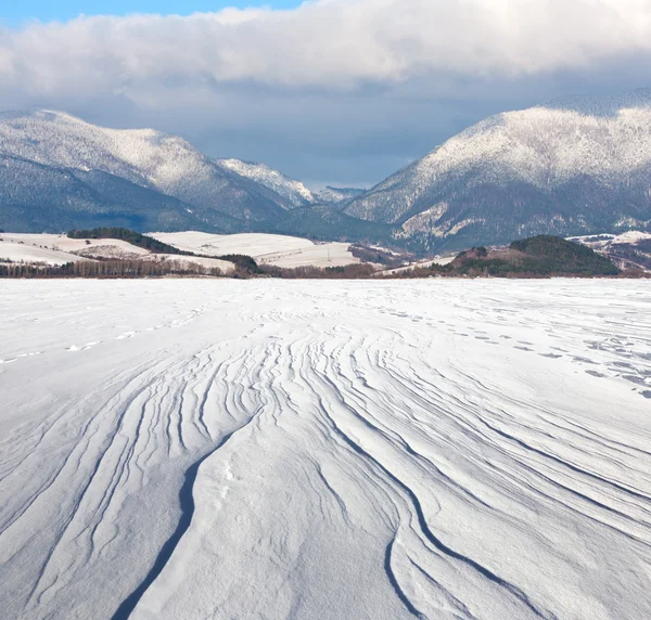 Prado nevado sob montanhas — Fotografia de Stock