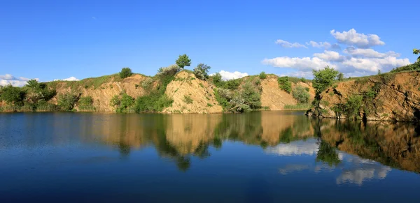 Скалистый берег на голубом озере — стоковое фото