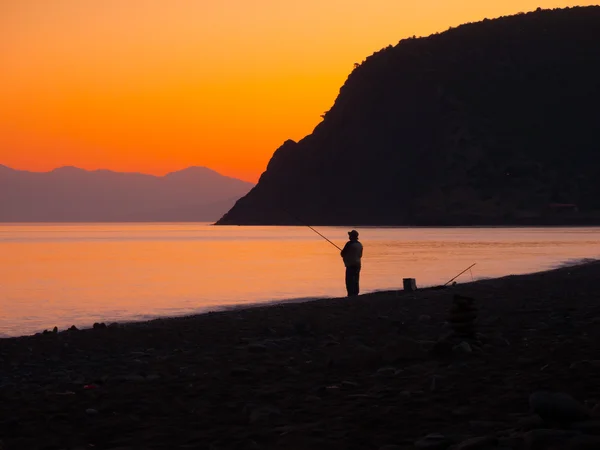 Fisherman catches a fish at sunset Stock Image